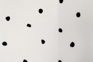 Minimalist image of abstract black dots on a white wall, offering a unique artistic design.
